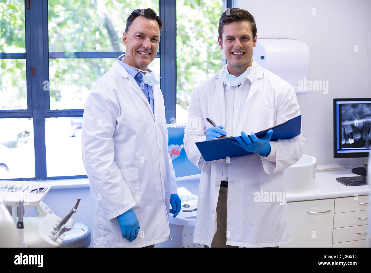 Portrait of happy dentists standing with file in clinic Stock Photo
