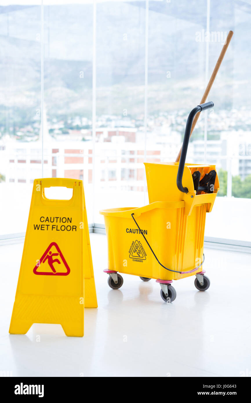 Sigh board with mop bucket in room against glass Stock Photo