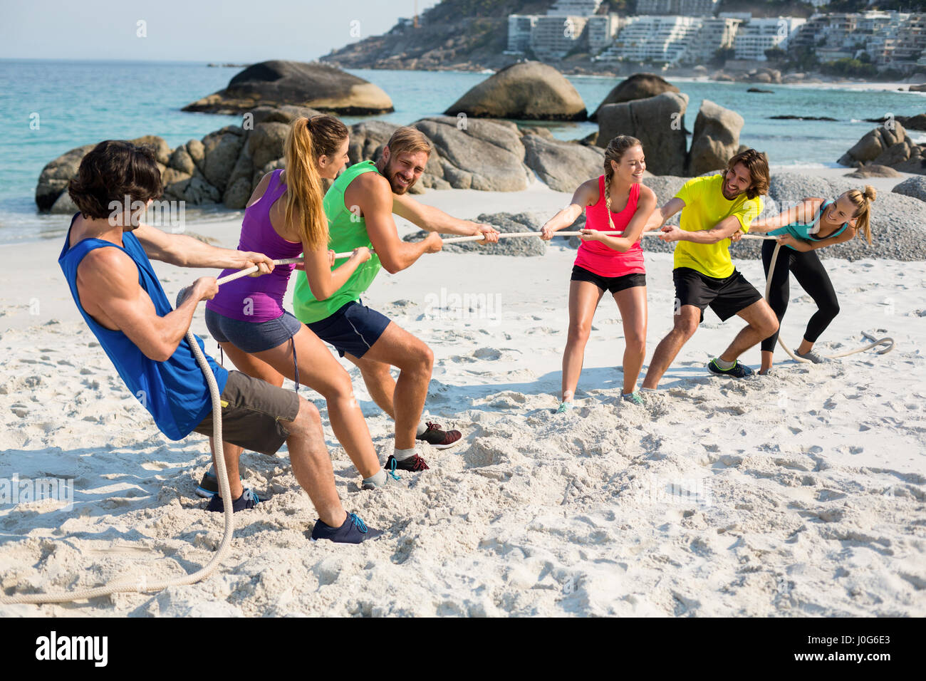 Full length of friends playing tug of war on shore at beach Stock Photo ...
