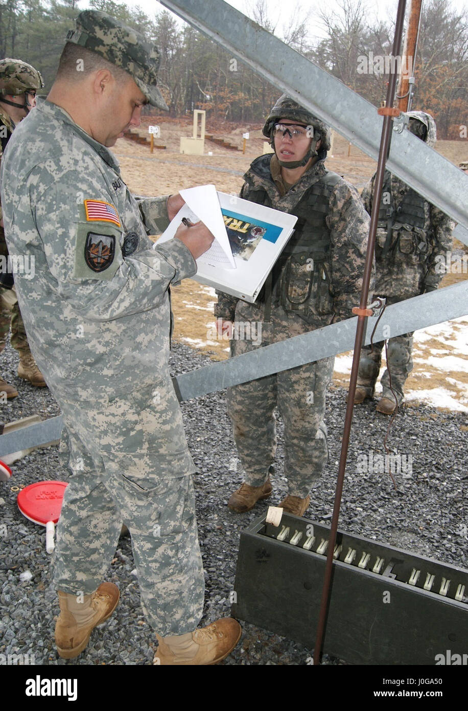 Master Sgt. William Buttrey records competitor Staff Sgt. Marcy DiOssi's weapons score at the 9mm pistol range at Fort Devens, Massachusetts, April 4, 2017, as part of the 2017 Joint 80th Training Command and 99th Regional Support Command Best Warrior Competition. Stock Photo