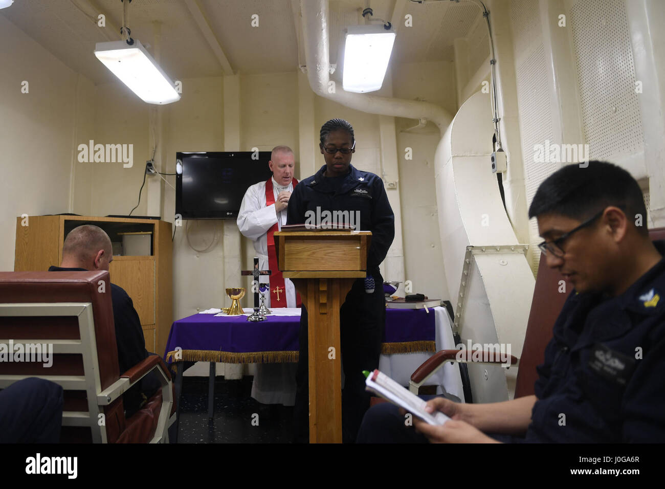 170404-N-ME988-069 5TH FLEET AREA OF OPERATIONS (April 4, 2017) Logistics Specialist 2nd Class Christie J. Martinez, a lay leader aboard the amphibious dock landing ship USS Carter Hall (LSD 50), reads scripture during Roman Catholic mass in celebration of the Eucharist in the ship’s Gator Chapel. The ship is currently deployed with the Bataan Amphibious Ready Group in the U.S. 5th Fleet area of operations in support of maritime security operations designed to reassure allies and partners and preserve the freedom of navigation and the free flow of commerce in the region. (U.S. Navy photo by Ma Stock Photo