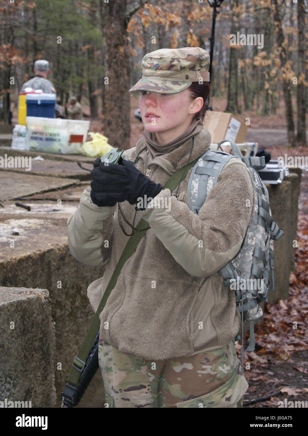 Competitor Spc. Dakota Dugan, with the 198th Army Band, 99th Regional Support Command, uses her compass as part of the land navigation event at Fort Devens, Massachusetts, April 5, 2017, as part of the 2017 Joint 80th Training Command and 99th RSC Best Warrior Competition. Stock Photo