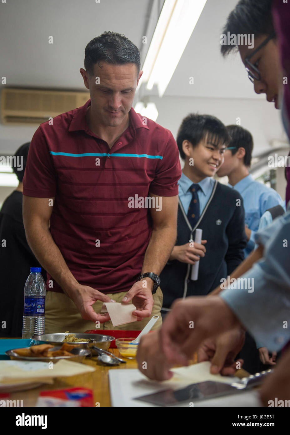 170410-N-LI768-366  HONG KONG (April 10, 2017) Staff Sgt. Carson Clover, assigned to Marine Medium Tiltrotor Squadron (VMM) 163, embarked aboard the amphibious assault ship USS Makin Island (LHD 8), makes spring rolls as part of a cultural exchange between Makin Island Sailors and Marines and students at SHK Tsoi Kung Po secondary school in Hong Kong. Makin Island, with the embarked 11th Marine Expeditionary Unit, visited Hong Kong to experience the city's rich culture and history as part of ongoing operations in the Indo-Asia-Pacific region. (U.S. Navy photo by Mass Communication Specialist 3 Stock Photo