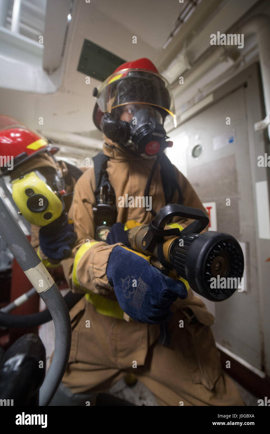 170328-N-PP996-060 SOUTH CHINA SEA (March 28, 2017) Gas Turbine System Technician Fireman Nicholas Watkins, from Savannah, Georgia, fights a simulated fire during a damage control drill aboard Arleigh Burke-class guided-missile destroyer USS Michael Murphy (DDG 112). Michael Murphy is on a regularly scheduled Western Pacific deployment with the Carl Vinson Carrier Strike Group as part of the U.S. Pacific Fleet-led initiative to extend the command and control functions of U.S. 3rd Fleet. U.S. Navy aircraft carrier strike groups have patrolled the Indo-Asia-Pacific regularly and routinely for mo Stock Photo