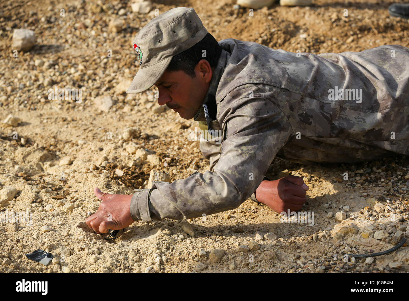 An Iraqi security forces soldier removes debris to search for a hidden simulated improvised explosive device during counter-IED training at Al Asad Air Base, Iraq, March 29, 2017.  This training is part of the overall Combined Joint Task Force – Operation Inherent Resolve building partner capacity mission by training and improving the capability of partnered forces fighting ISIS. CJTF- OIR is the global Coalition to defeat ISIS in Iraq and Syria. (U.S. Army photo by Sgt. Lisa Soy) Stock Photo