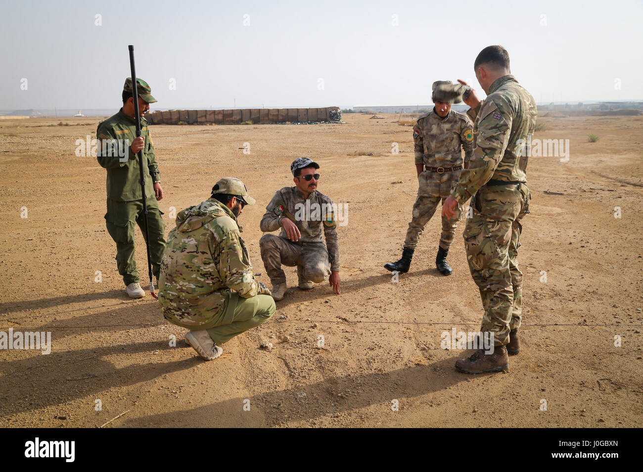 A British trainer, deployed in support of Combined Joint Task Force – Operation Inherent Resolve, explains to Iraqi security forces soldiers how to detect an improvised explosive device on a patrol during counter-IED training at Al Asad Air Base, Iraq, March 29, 2017. This training is part of the overall CJTF- OIR building partner capacity mission by training and improving the capability of partnered forces fighting ISIS. CJTF- OIR is the global Coalition to defeat ISIS in Iraq and Syria. (U.S. Army photo by Sgt. Lisa Soy) Stock Photo