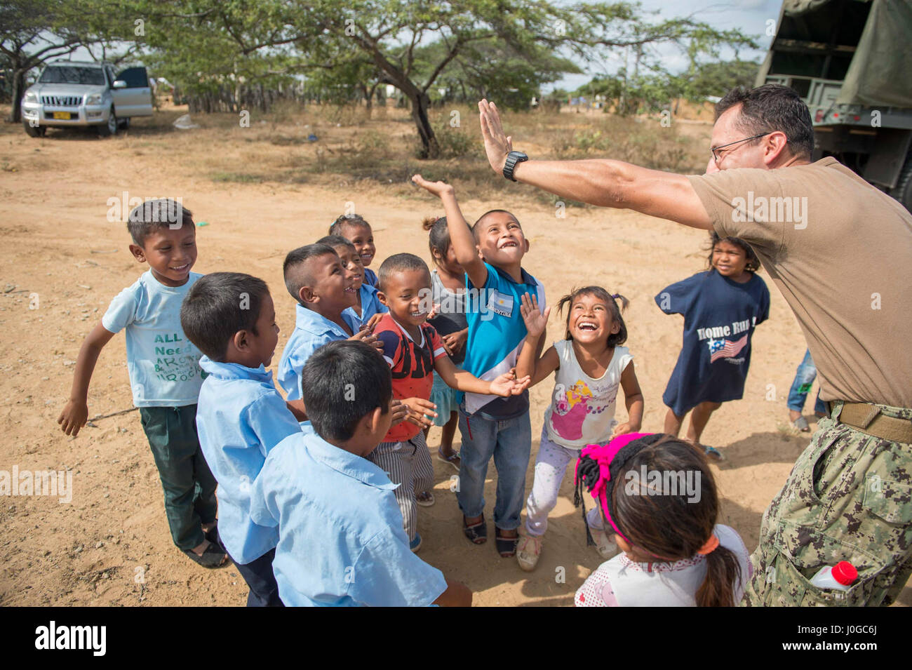170330-N-YL073-061 MAYAPO, Colombia (March 30, 2017) - Engineering Aide 2nd Class Gabriel Jimenez, a native of Colombia assigned to Construction Battalion Maintenance Unit (CBMU) 202, high fives children from a Wayuu tribe in Mayapo, Colombia, during Continuing Promise 2017 (CP-17). CP-17 is a U.S. Southern Command-sponsored and U.S. Naval Forces Southern Command/U.S. 4th Fleet-conducted deployment to conduct civil-military operations including humanitarian assistance, training engagements, medical, dental, and veterinary support in an effort to show U.S. support and commitment to Central and  Stock Photo