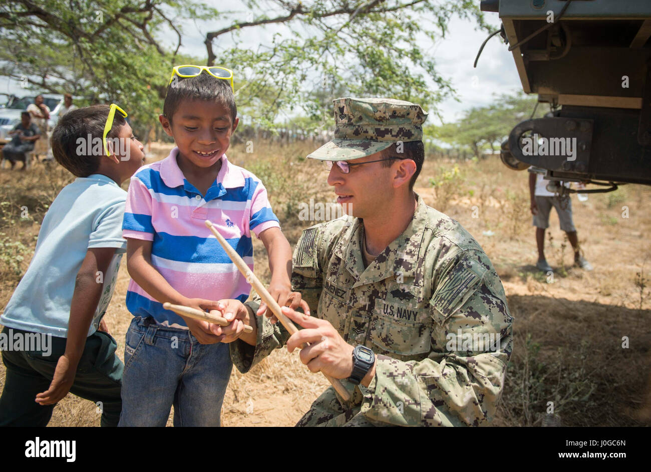 170330-N-YL073-377 MAYAPO, Colombia (March 30, 2017) - Engineering Aide 2nd Class Gabriel Jimenez (left), a native of Colombia assigned to Construction Battalion Maintenance Unit (CBMU) 202, teaches a Wayuu child how to use drumsticks during Continuing Promise 2017's (CP-17) visit to Mayapo, Colombia. CP-17 is a U.S. Southern Command-sponsored and U.S. Naval Forces Southern Command/U.S. 4th Fleet-conducted deployment to conduct civil-military operations including humanitarian assistance, training engagements, medical, dental, and veterinary support in an effort to show U.S. support and commitm Stock Photo