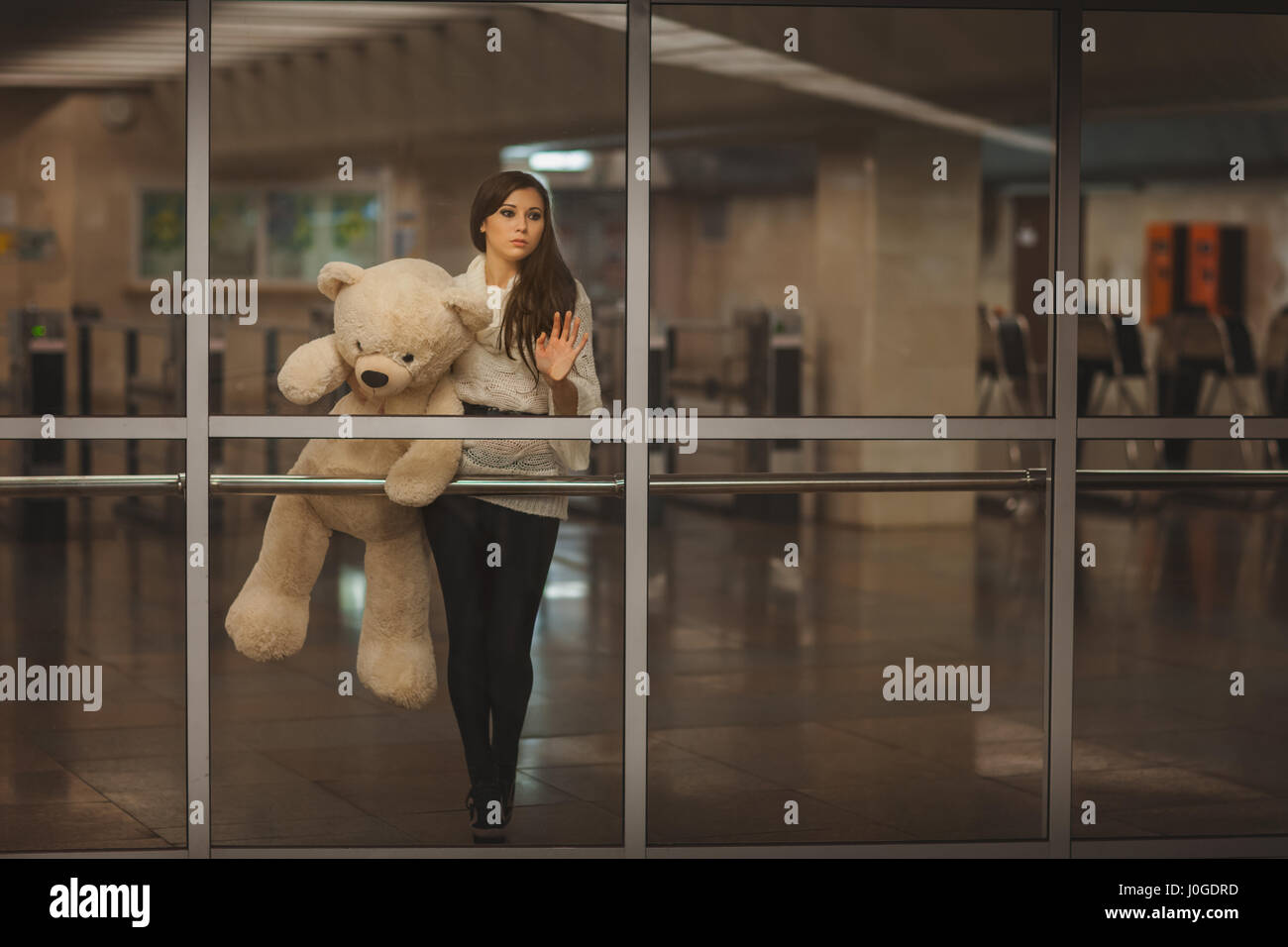 Girl with teddy bear in his hands waving goodbye hand, it is very sad. Stock Photo