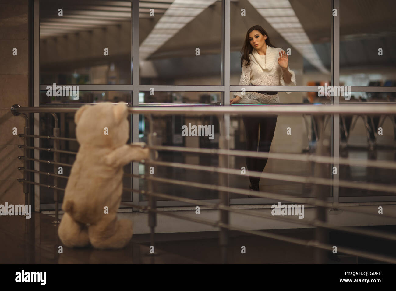 Sad girl waving, she says goodbye with a teddy bear and it's very sad. Stock Photo