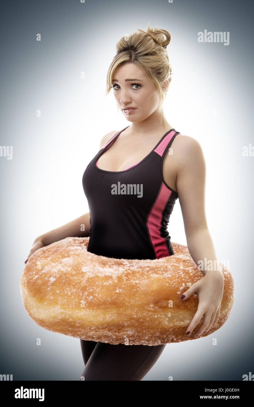 fitness woman with a large donut around her waist symbolize putting on weight Stock Photo