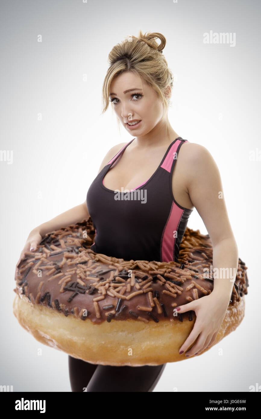 fitness woman with a large donut around her waist symbolize putting on weight Stock Photo