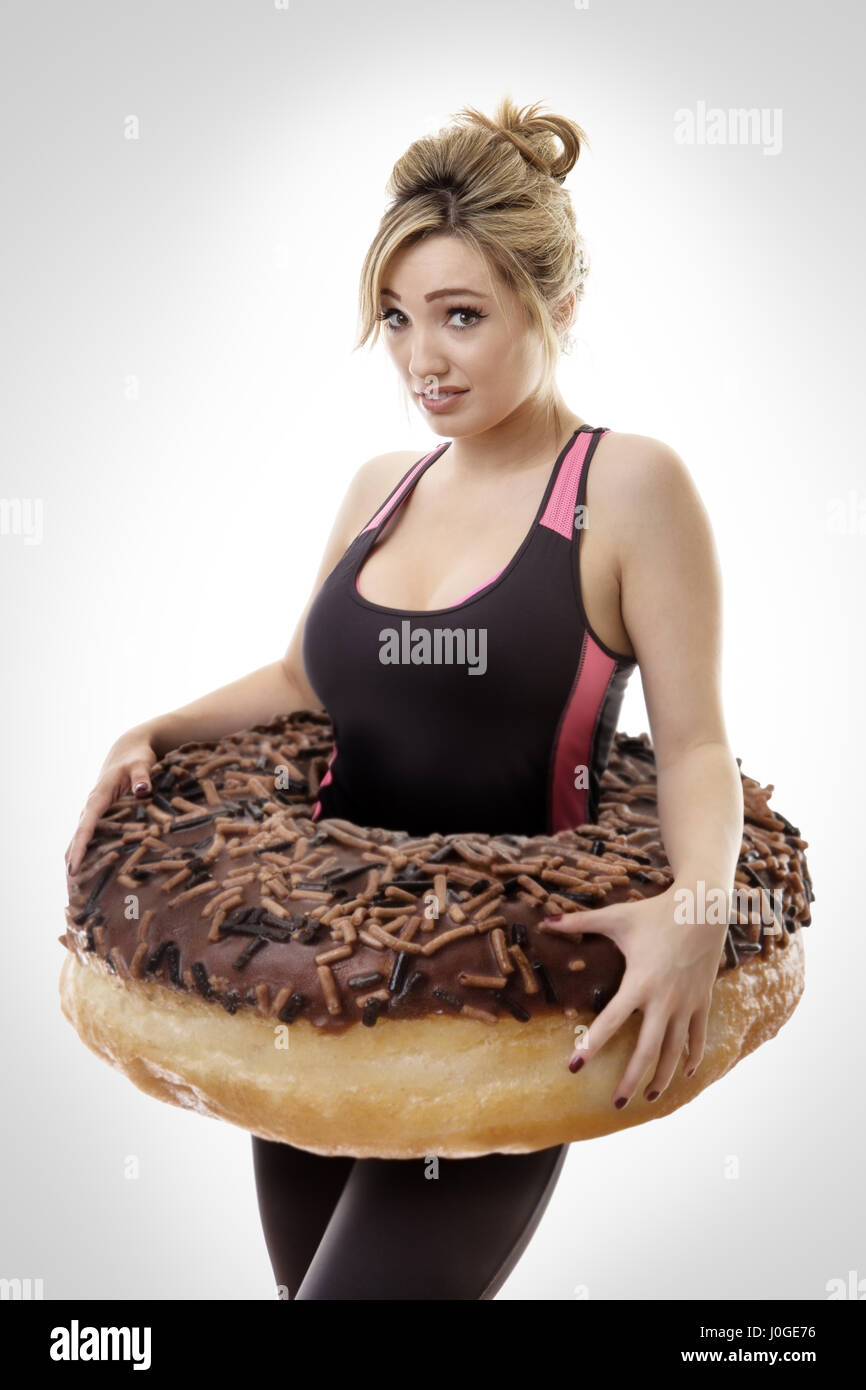 fitness woman with a large donut around her waist symbolize putting on weight Stock Photo