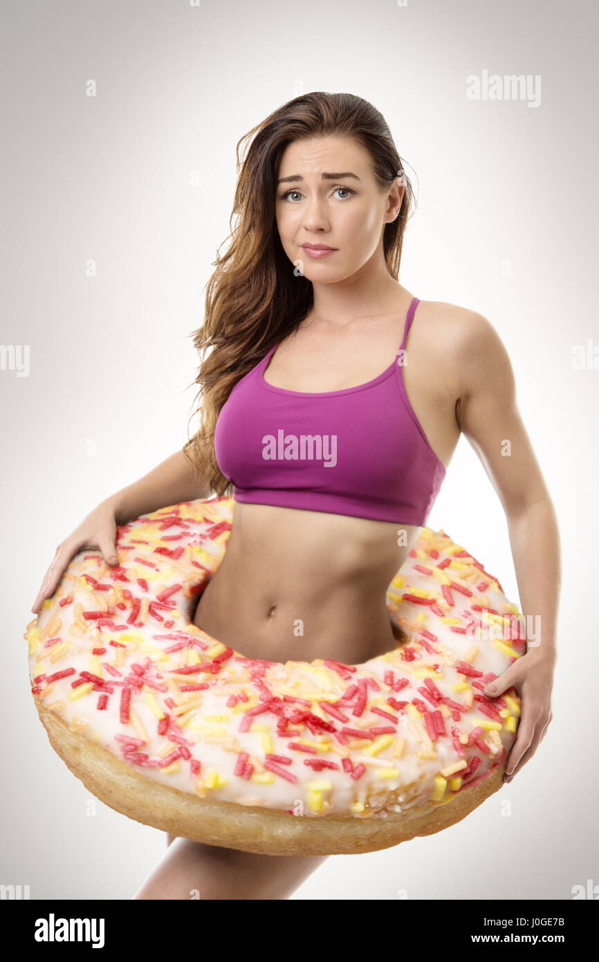 fitness woman with a large donut around her waist symbolize putting on weight Stock Photo