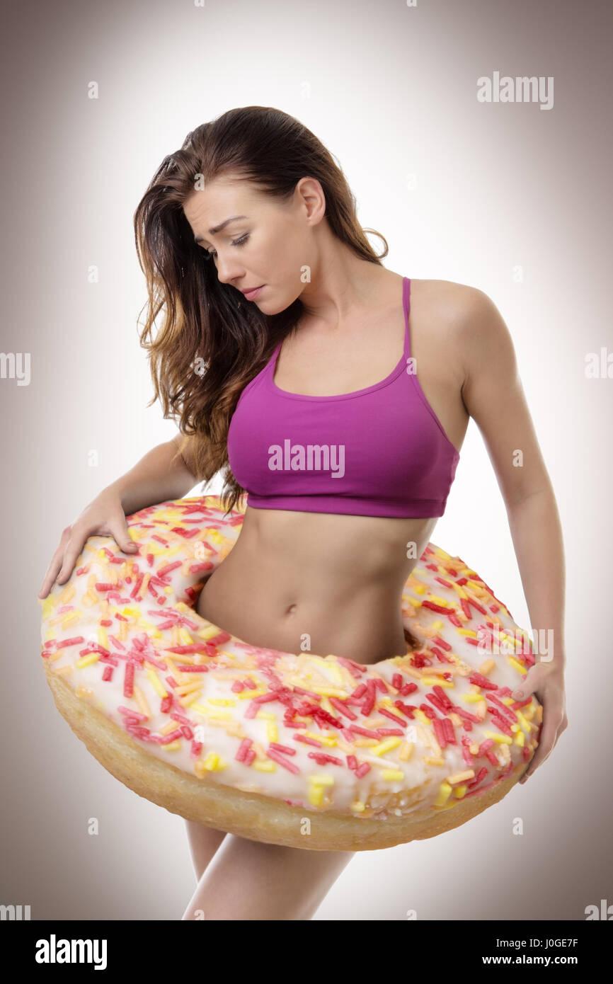 fitness woman with a large donut around her waist symbolize putting on weight Stock Photo