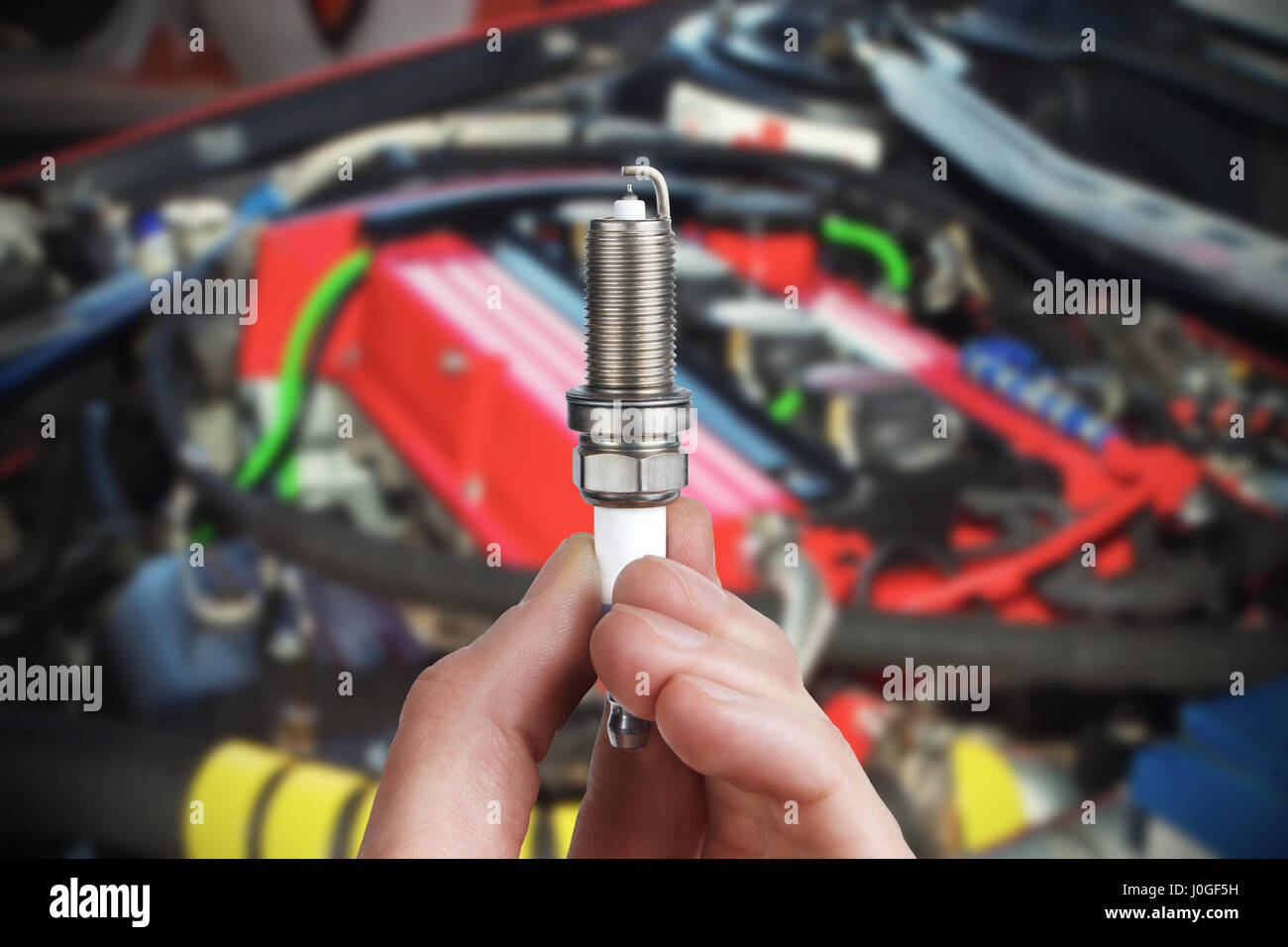 Mechanic holds a spare part spark plug in his hand. Auto part spark plug close-up. Stock Photo