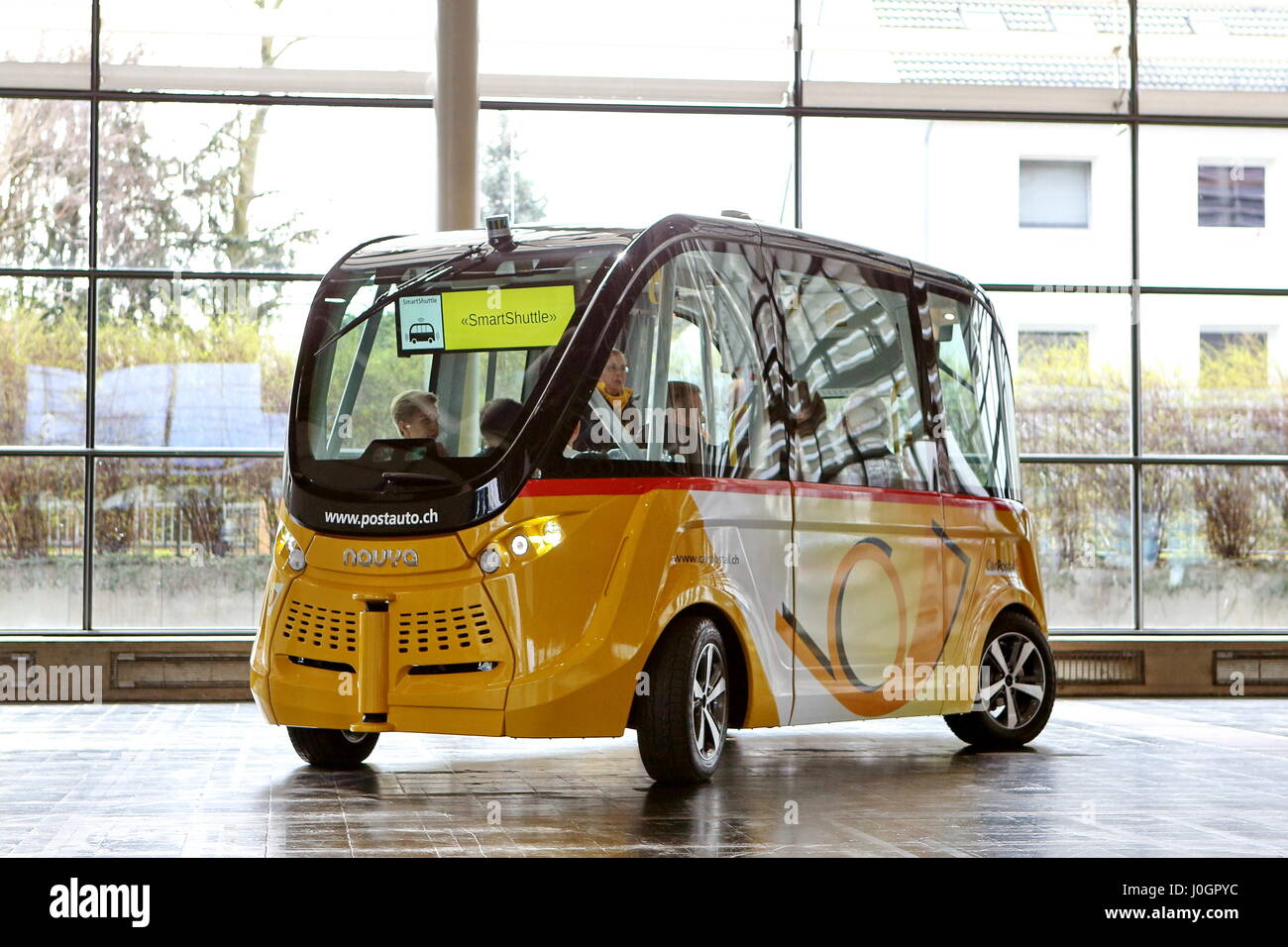 Hanover, Germany. 21th March, 2017. self-driving electric minibus by PostAuto Switzerland invides fair visitors for a test drive with this 'SmartShuttle' through fair hall 13. This autonomous bus (Model name: Arma) is manufactured by Navya SAS (France), is considered first autonomous series vehicle for local trafiic, in usage since 2016 (e.g. Switzerland, France), max. 15 persons, max. speed 45 km/h. CeBIT 2017, ICT trade fair, lead theme 'd!conomy - no limits'. Photocredit: Christian Lademann Stock Photo