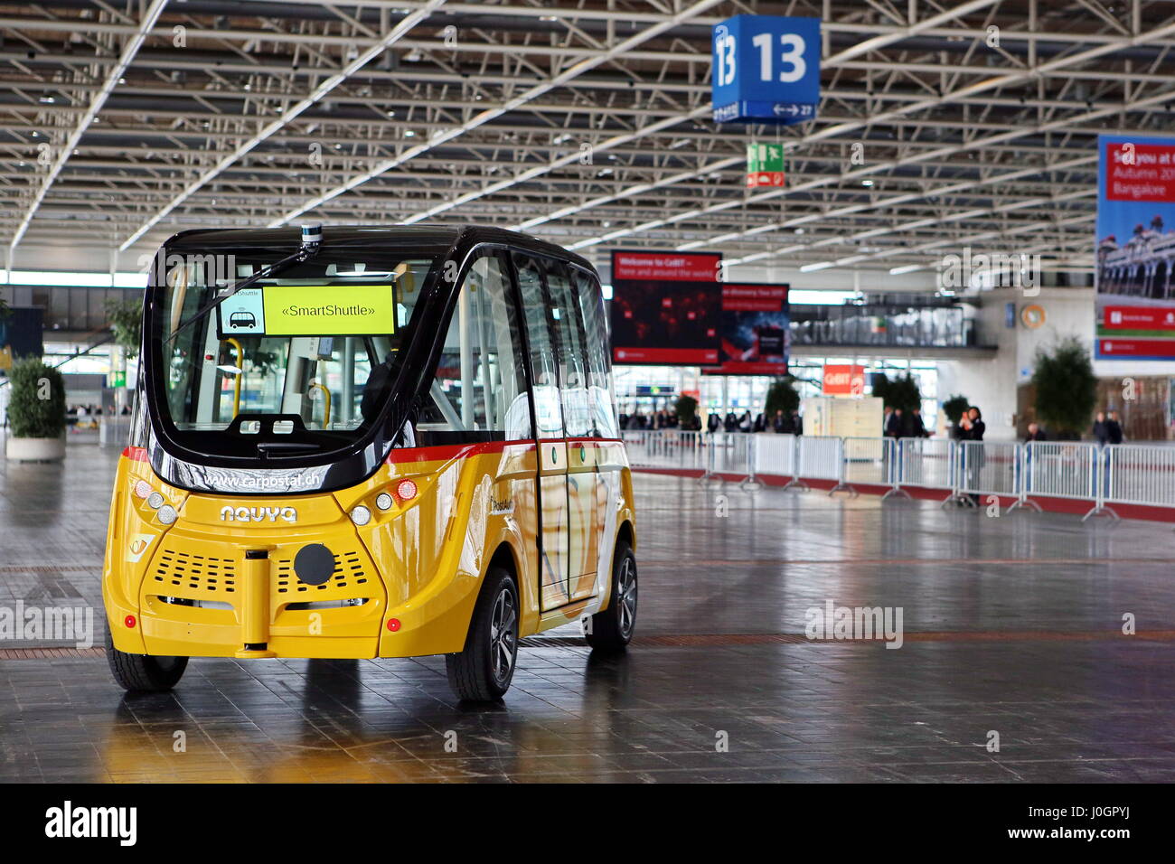 Hanover, Germany. 21th March, 2017. self-driving electric minibus by PostAuto Switzerland invides fair visitors for a test drive with this 'SmartShuttle' through fair hall 13. This autonomous bus (Model name: Arma) is manufactured by Navya SAS (France), is considered first autonomous series vehicle for local trafiic, in usage since 2016 (e.g. Switzerland, France), max. 15 persons, max. speed 45 km/h. CeBIT 2017, ICT trade fair, lead theme 'd!conomy - no limits'. Photocredit: Christian Lademann Stock Photo