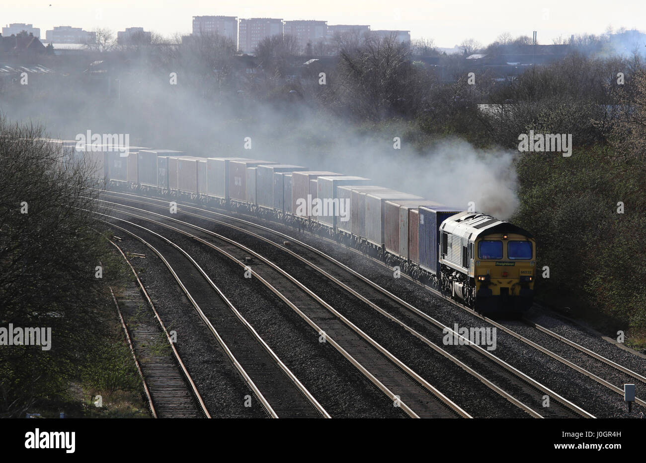A diesel railway locomotive emitting a cloud of exhaust smoke as it travels. Stock Photo