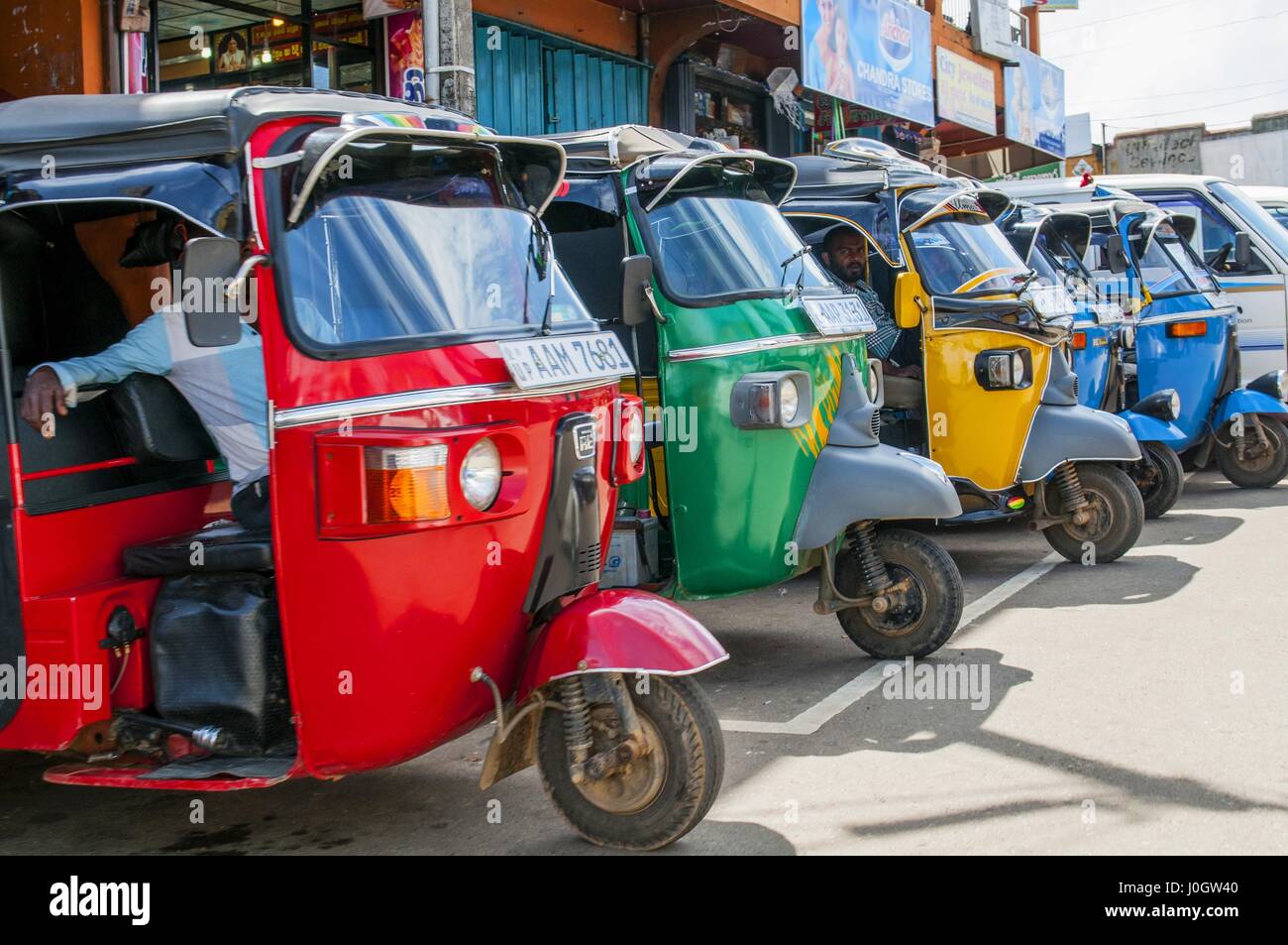 Row of red, green, yello and blue empty tuk-tuks waits for passengers in Sri Lanka. Tuk-tuk is a popular asian transport as taxi. Stock Photo