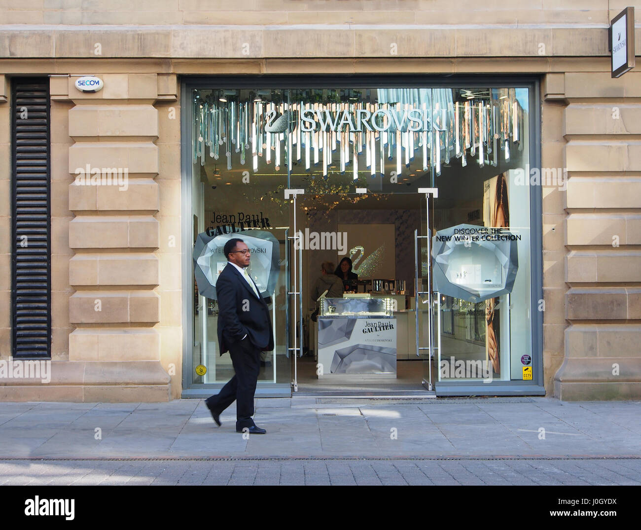 Manchester city centre high street jewellery shop shops Swarovski, showing  the exterior, entrance and interior with an ethnic male man walking past  Stock Photo - Alamy