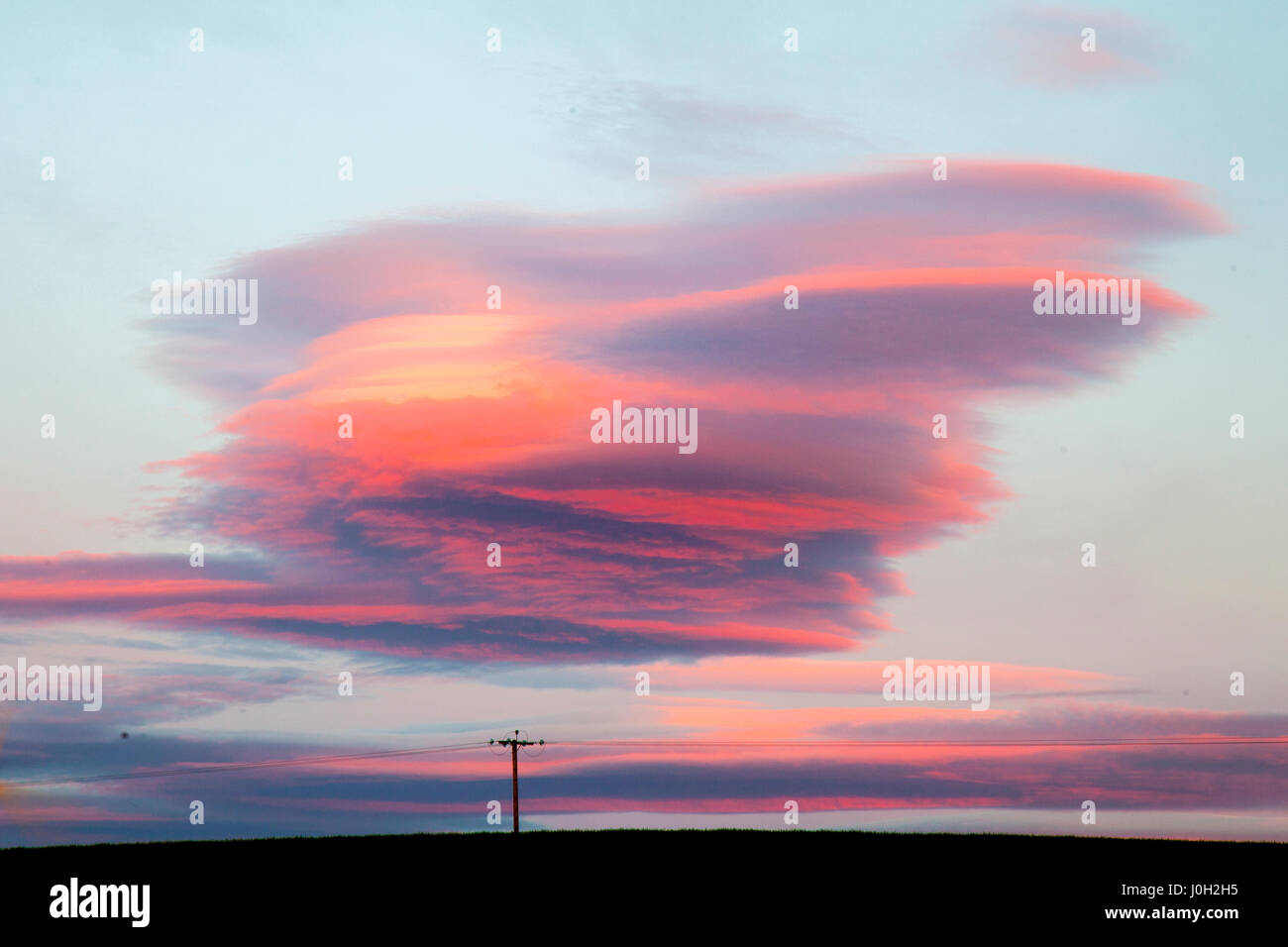Lenticular 'UFO' Clouds, mountain waves in the air form at dawn in Stonehaven, Scotland, UK UK Weather. 13th April, 2017.  Lenticular clouds are stationary lens-shaped clouds that form in the troposphere, normally in perpendicular alignment to the wind direction and have been regularly confused for UFOs throughout history due to the their smooth, round or oval structure. A distinctive cloud formation resembling lenses and are thought to be an explanation for some supposed UFO sightings. Stock Photo