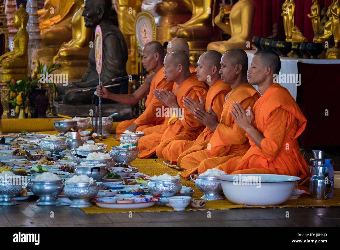 Buddhist monks pray to bless the food given as alms during Songkran