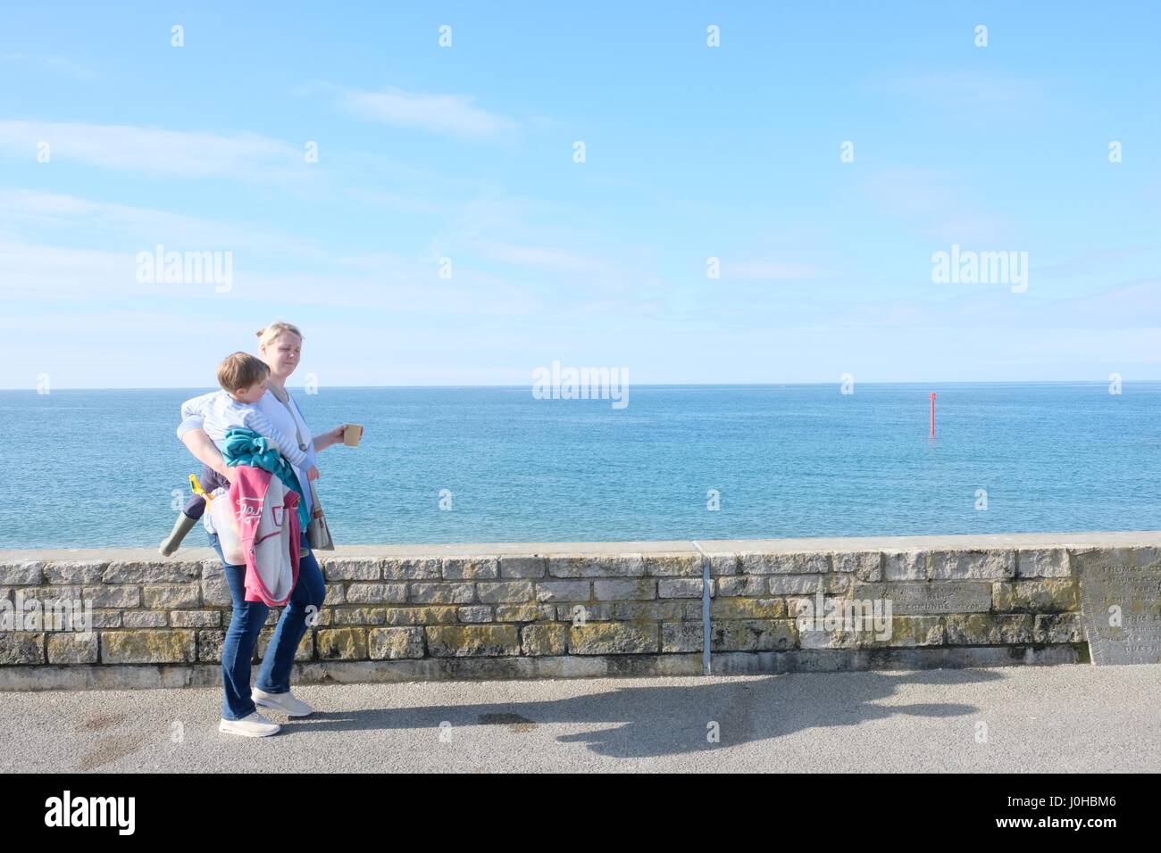 West Bay, Dorset, UK. 14th Apr, 2017. A mother and child make an early start towards the beach on a sunny bank Holliday Friday on the Dorset Coast Credit: Tom Corban/Alamy Live News Stock Photo