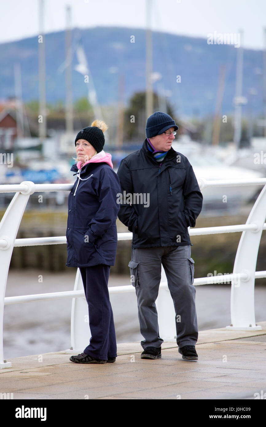 A man and woman standing together against railings at the harbour at