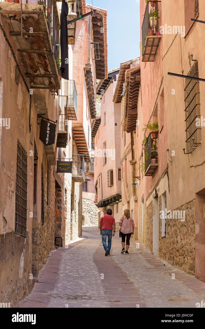 A couple walk through the narrow medieval streets with balconied houses wind through the Medieval Town of Albarracin, Teruel, Aragon, Spain Stock Photo