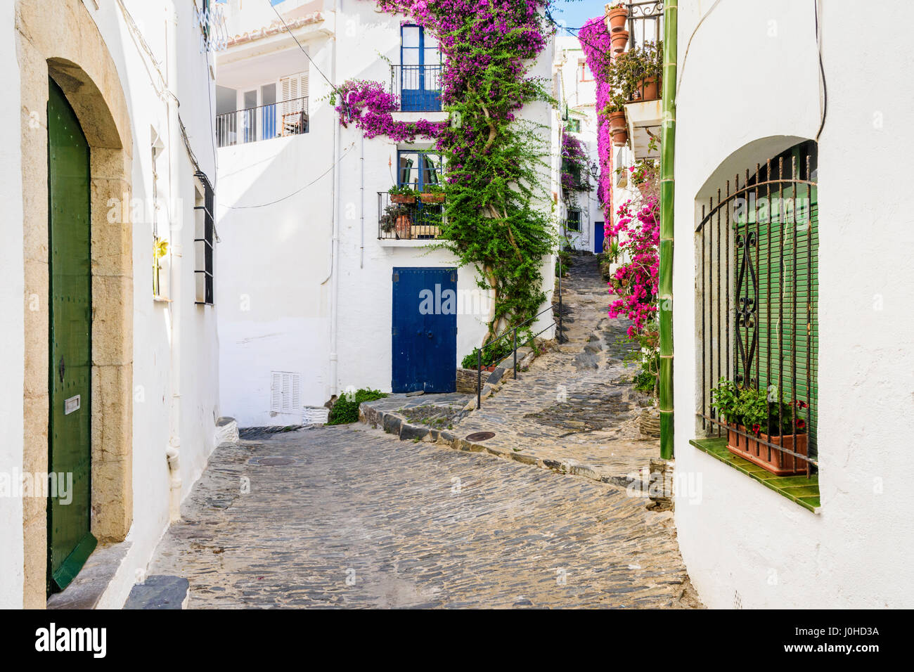 Whitewashed bougainvillea covered buildings and old town cobble streets of Cadaques Town, Costa Brava, Spain Stock Photo