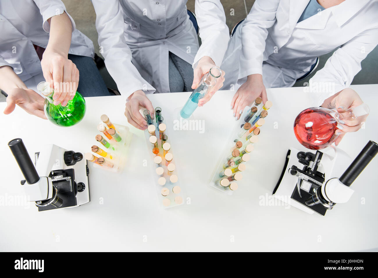 Top view of three female scientists holding chemical reagents in laboratory Stock Photo