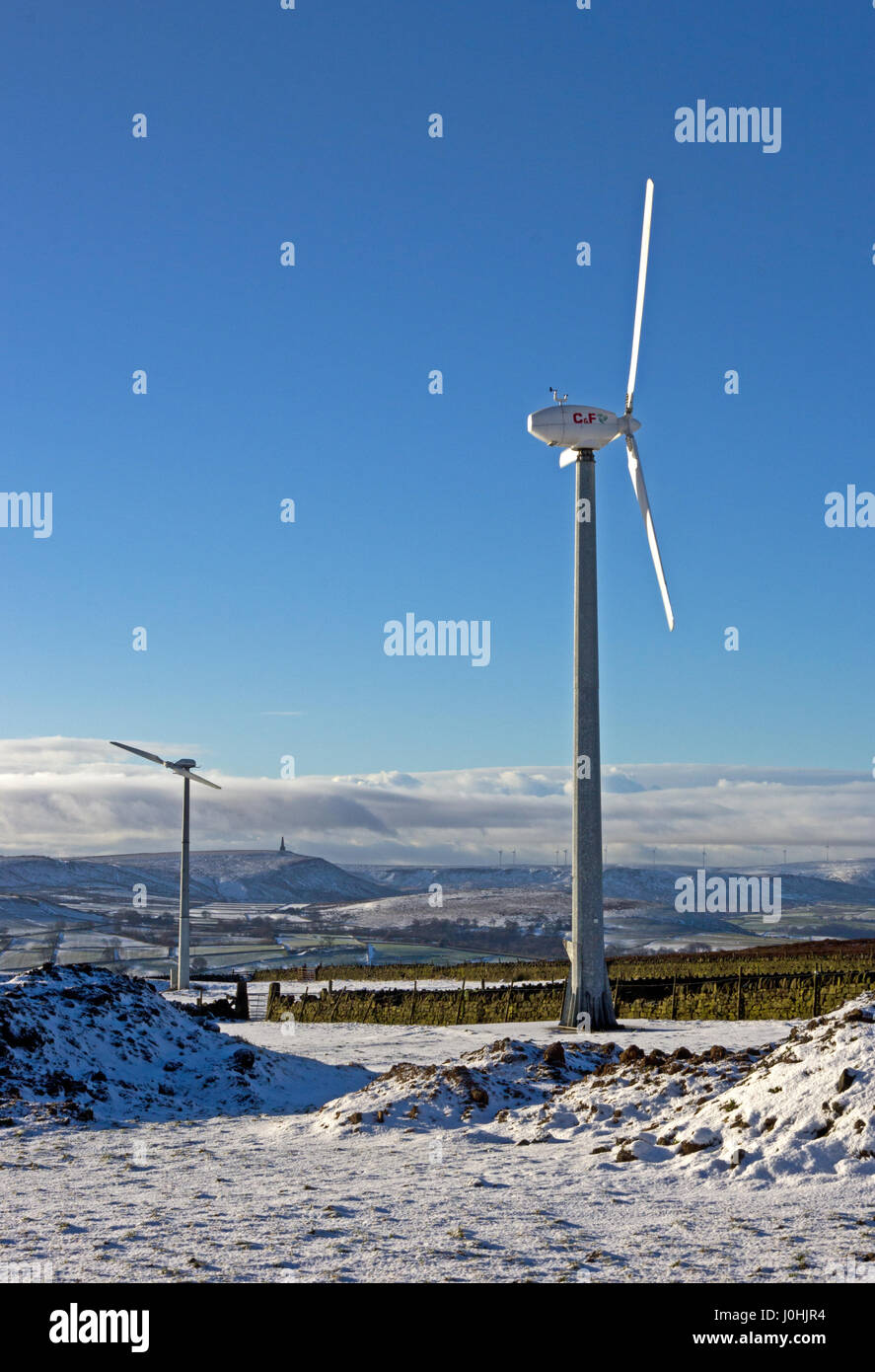 Wind turbines on Pennine hills above Hebden Bridge, in winter, with Stoodley Pike on horizon. Stock Photo