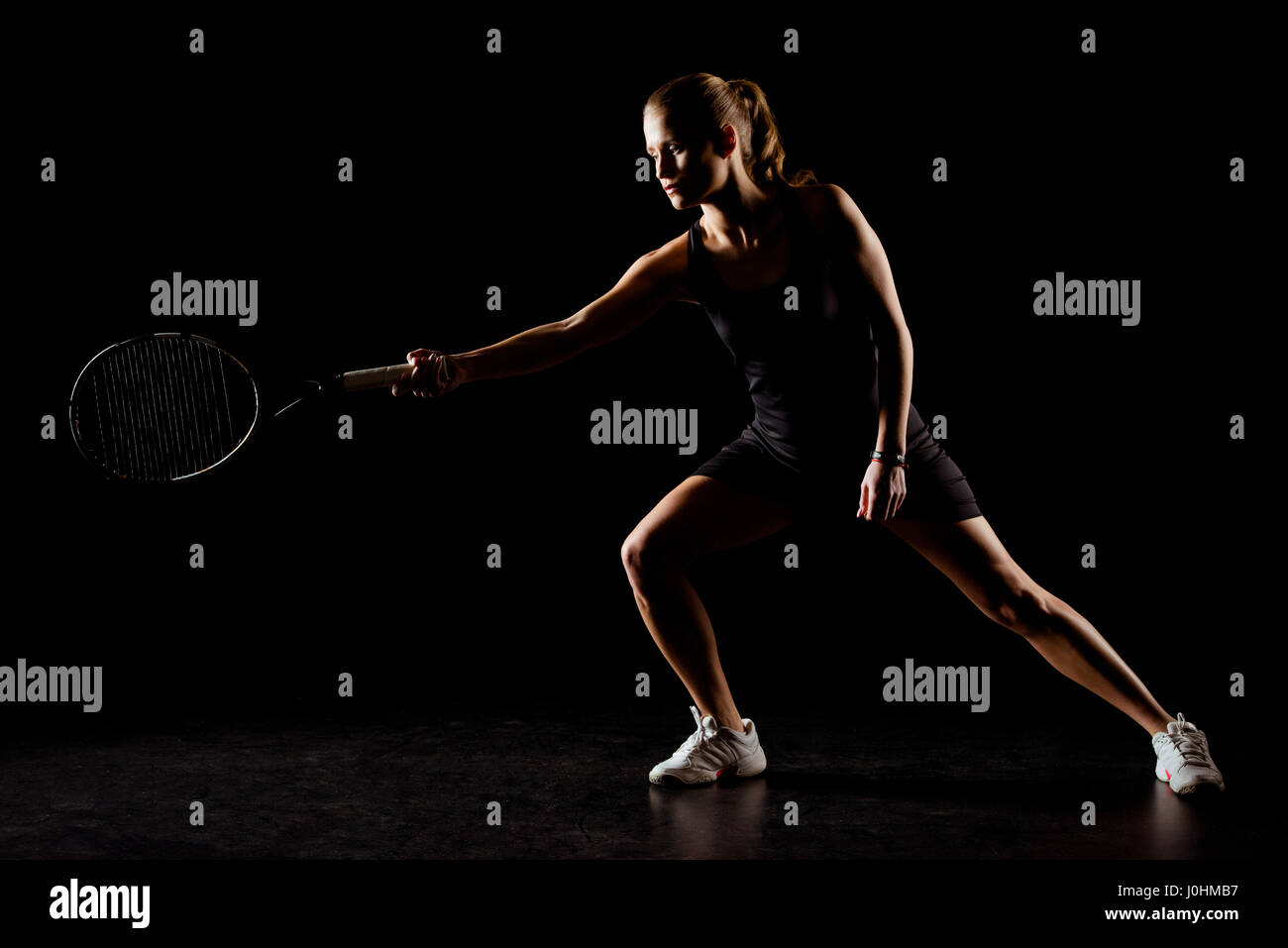 Photo Poses With Racket Sportive young woman in motion holding tennis racket on black Stock ...
