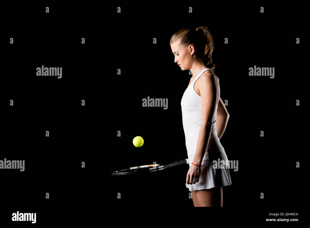 Side view of concentrated female tennis player hitting ball with racket ...