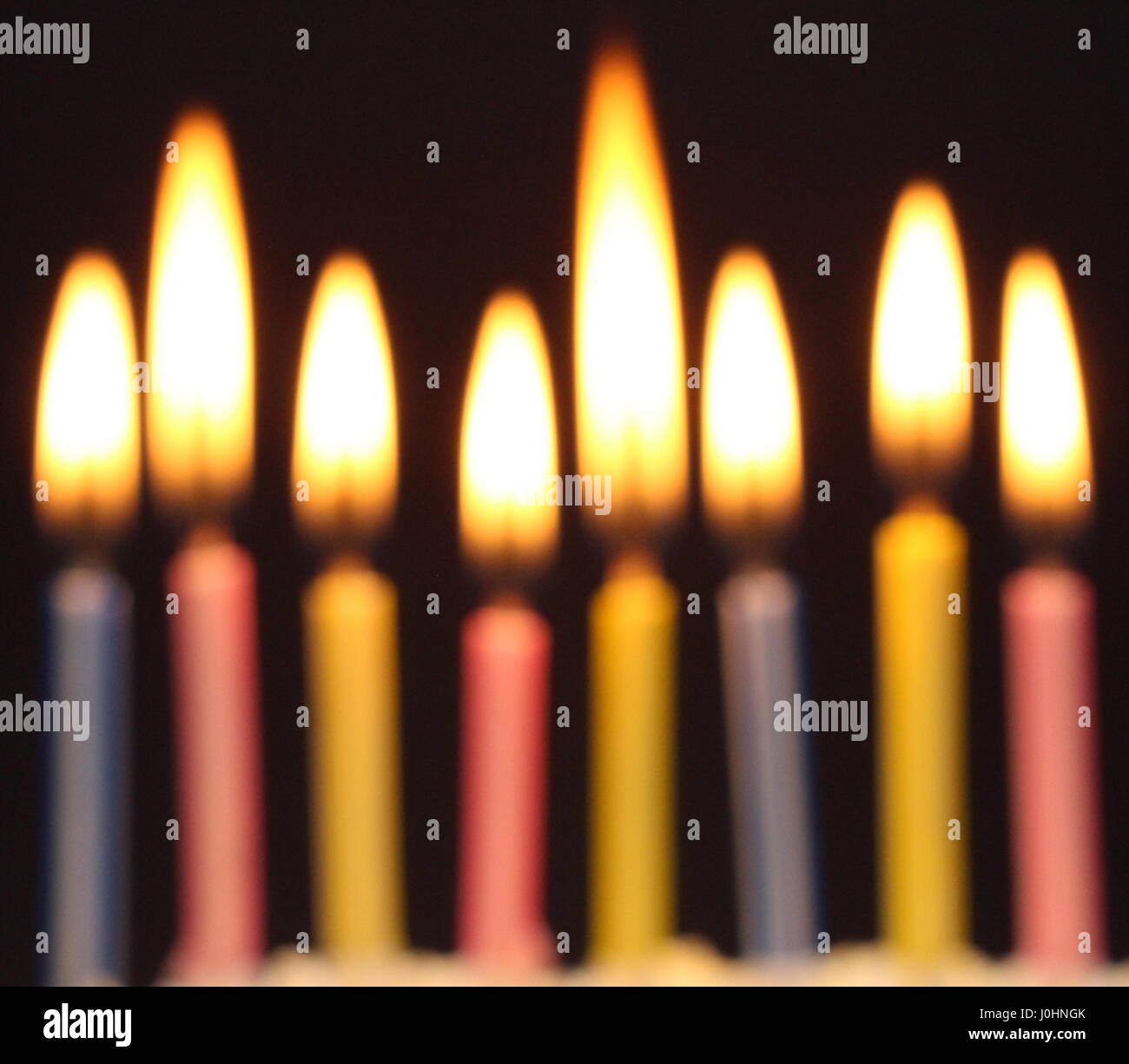 Eight birthday cake candles alight, against a black background