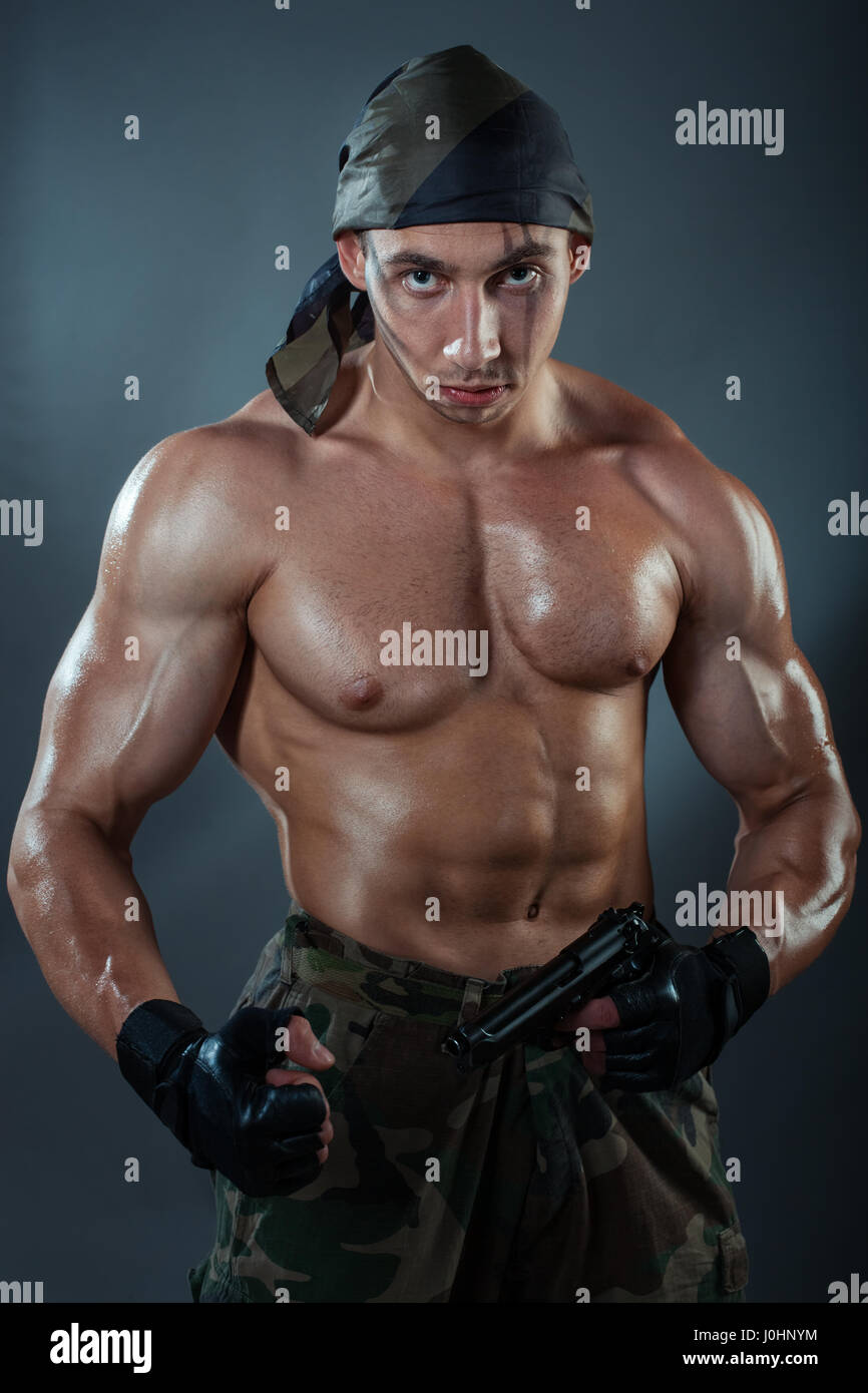 A man with huge muscles holding a gun. He had a serious face Stock