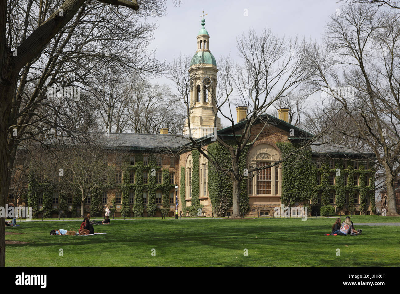 Princeton, NJ, USA - April 11, 2017: Princeton University Campus in spring. Nassau Hall and Cannon Green. Students sitting on the lawn on a sunny day. Stock Photo