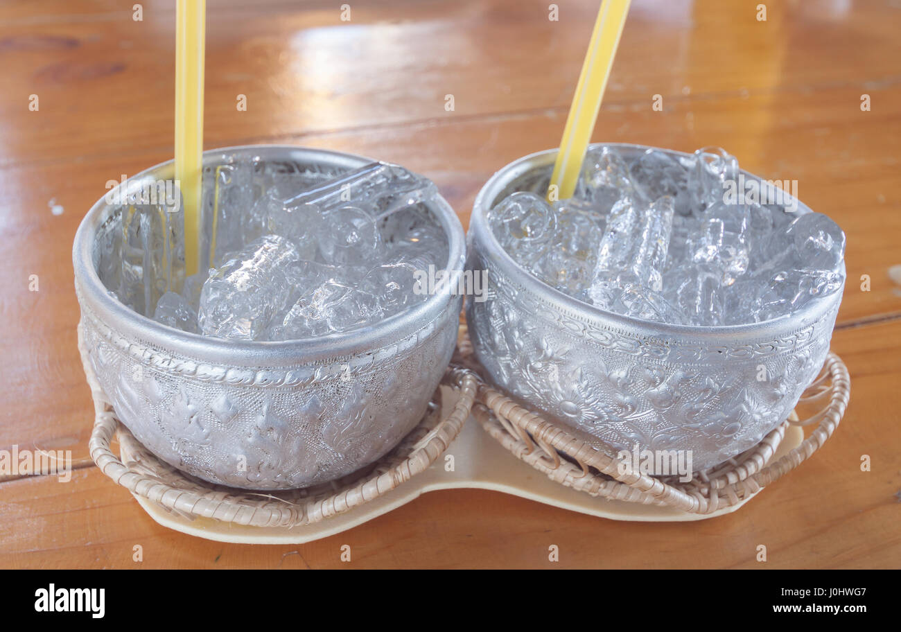 Aluminum bowl with ice cubes on wooden table Stock Photo