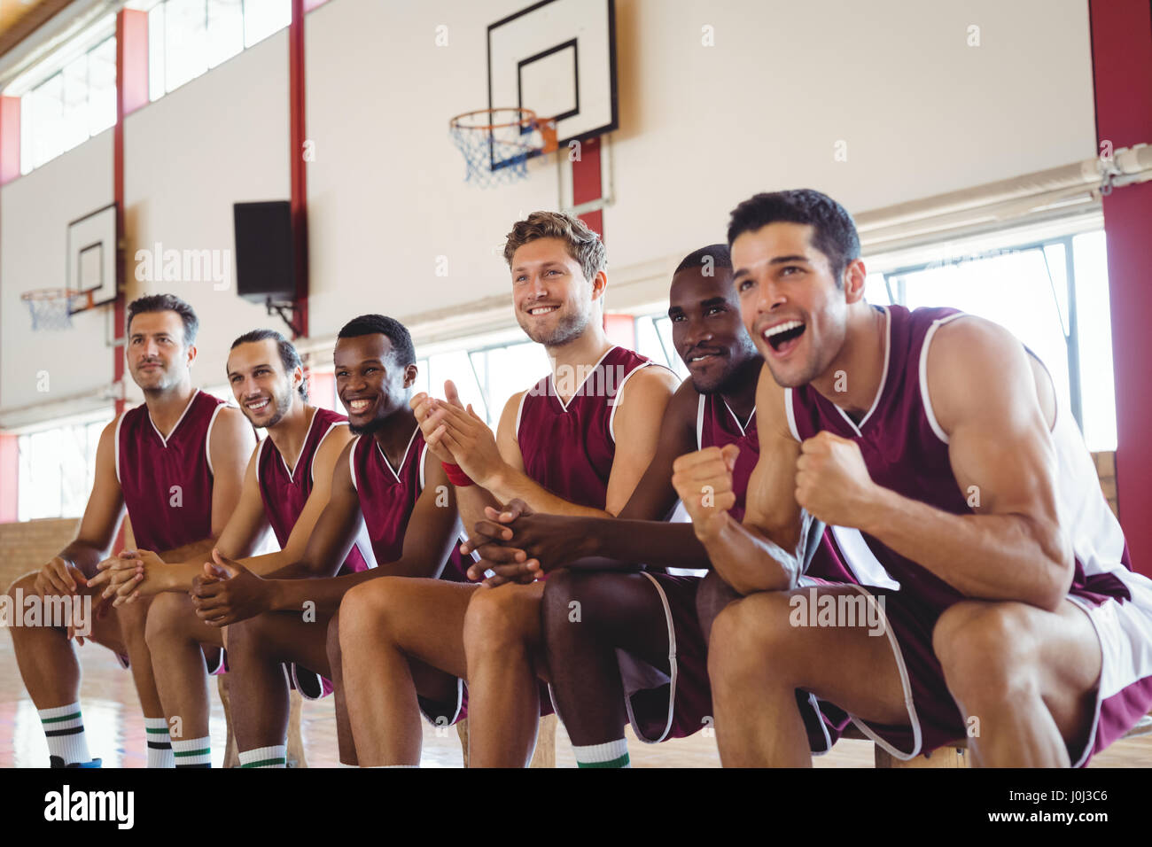 Excited basketball player sitting on bench in court Stock Photo