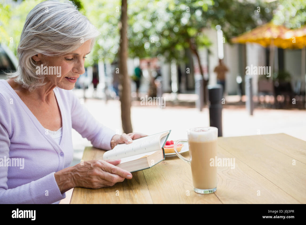 Senior woman reading a book in outdoor cafÃƒÂ© Stock Photo - Alamy