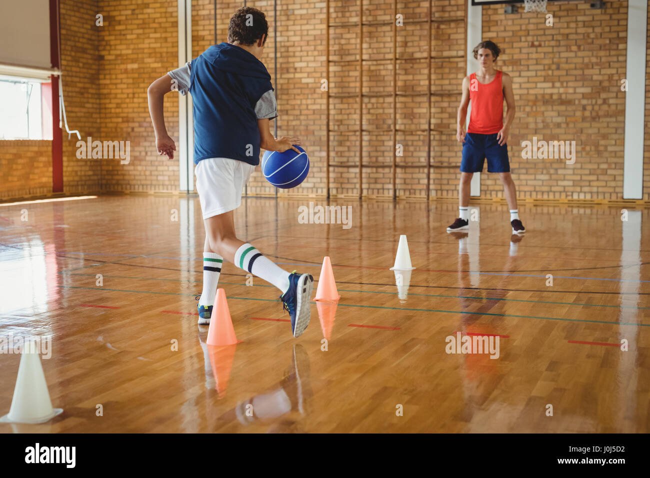 High school boys practicing football using cones for dribbling drill in the court Stock Photo