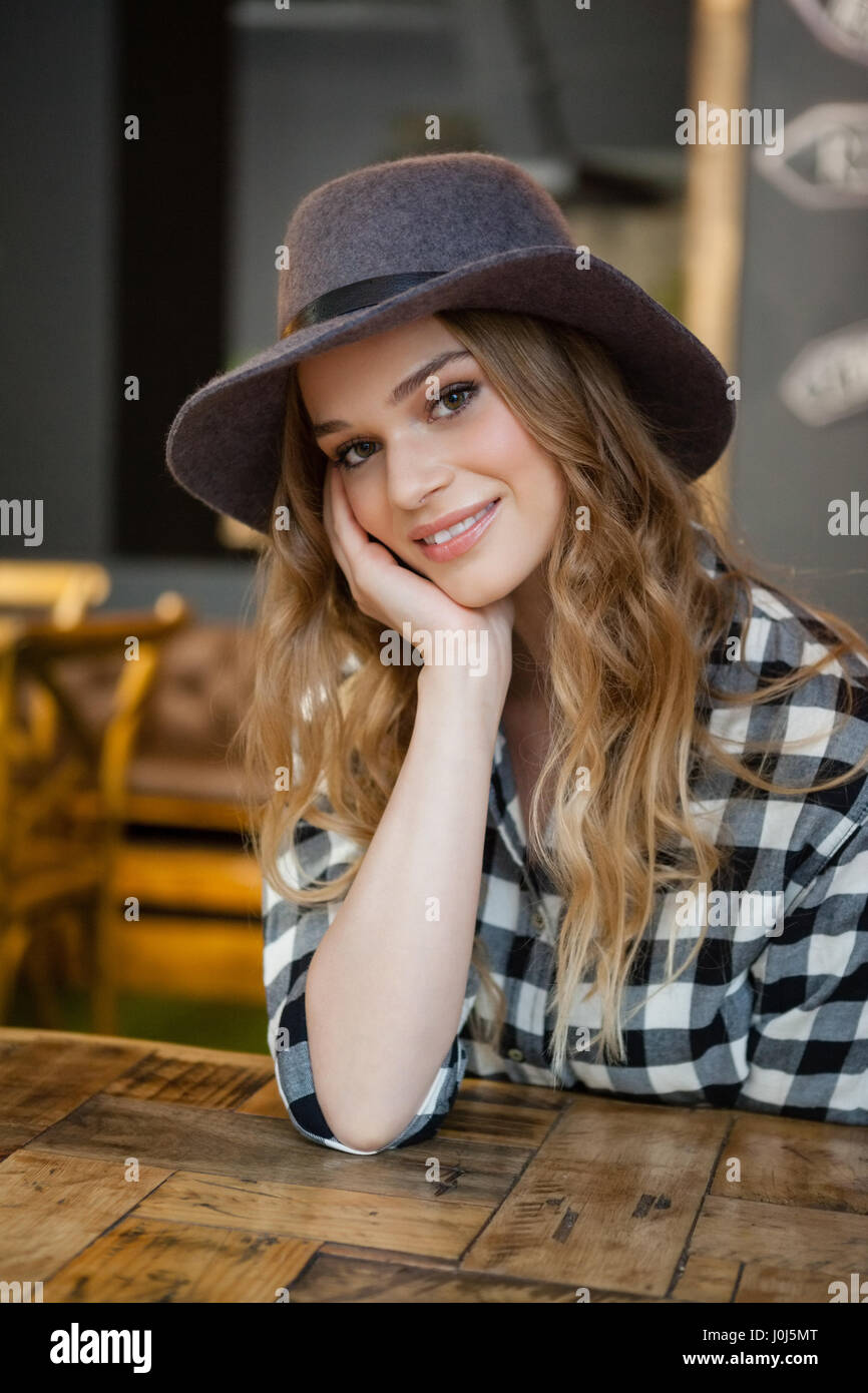 Portrait of smiling woman with hand on chin sitting at table in cafe Stock Photo