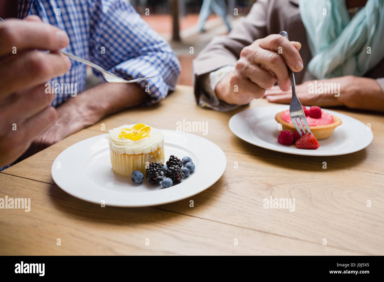 Senior couple having cupcake with blueberries and blackberries in outdoor cafÃƒÂ© Stock Photo