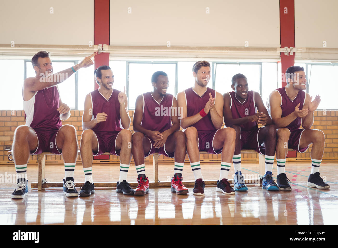 Excited Basketball Player Sitting On Bench In Court Stock Photo