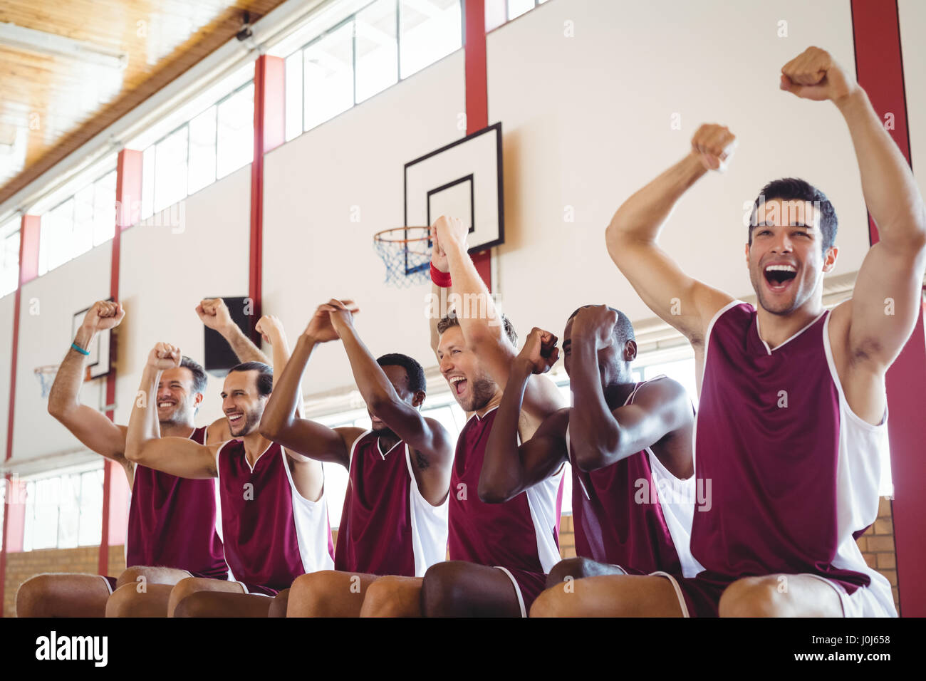 Excited basketball player sitting on bench in court Stock Photo