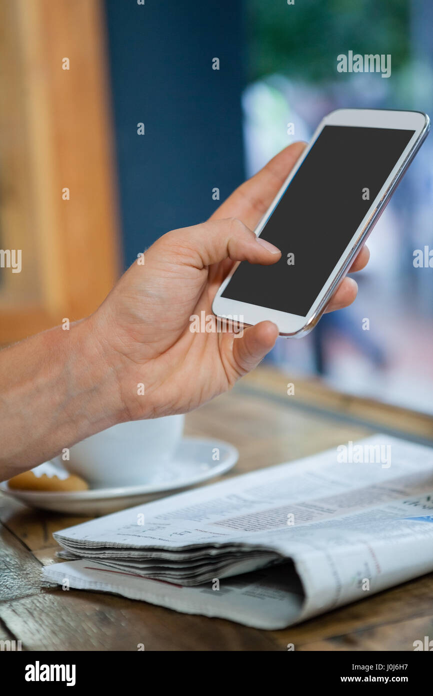 Cropped image of woman holding mobile phone at table in cafe Stock Photo