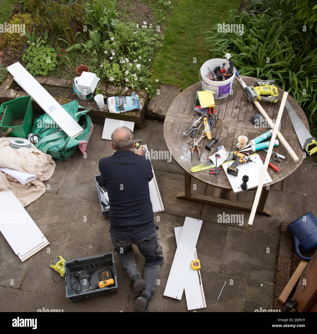 An overview of a handyman engaged in some DIY work on the garden patio