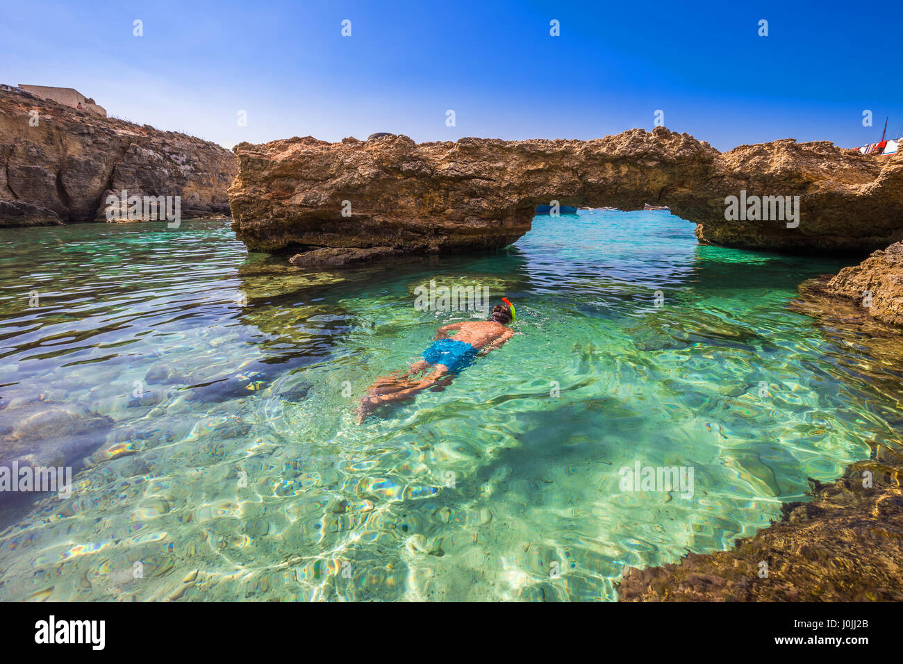 Blue Lagoon, Malta - Snorkeling tourist at the caves of the Blue Lagoon on the island of Comino on a bright sunny summer day with blue sky Stock Photo