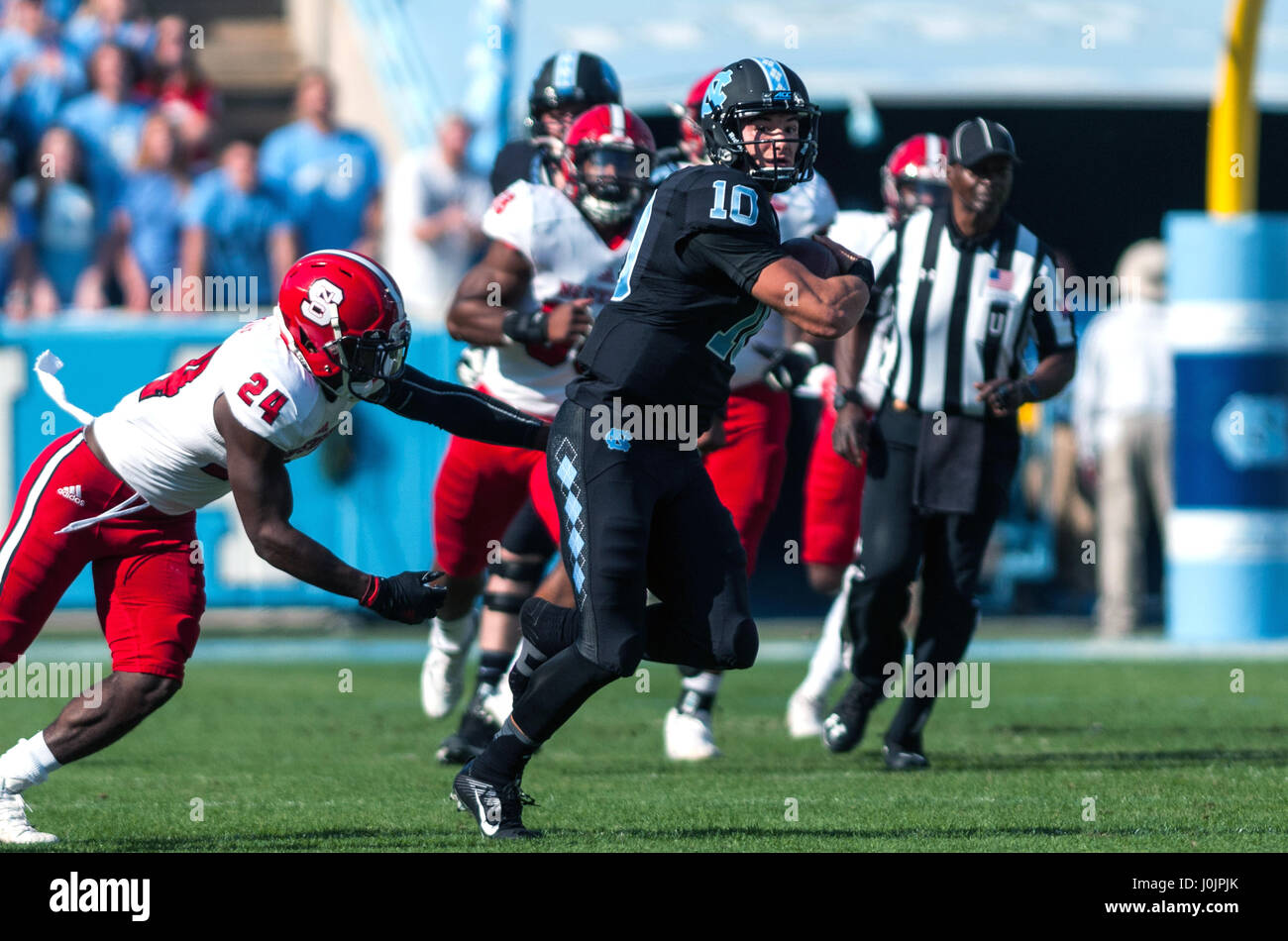 North Carolina Tar Heels quarterback Mitch Trubisky (10) eludes the grasp of North Carolina State Wolfpack safety Shawn Boone (24) during the first half of an NCAA football game between the North Carolina Tar Heels and the N.C. State Wolfpack at Kenan Memorial Stadium in Chapel Hill. Stock Photo
